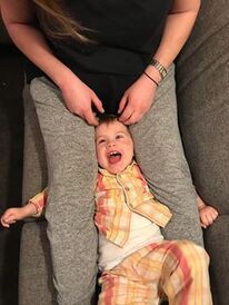 Toddler being restrained under parent's legs
